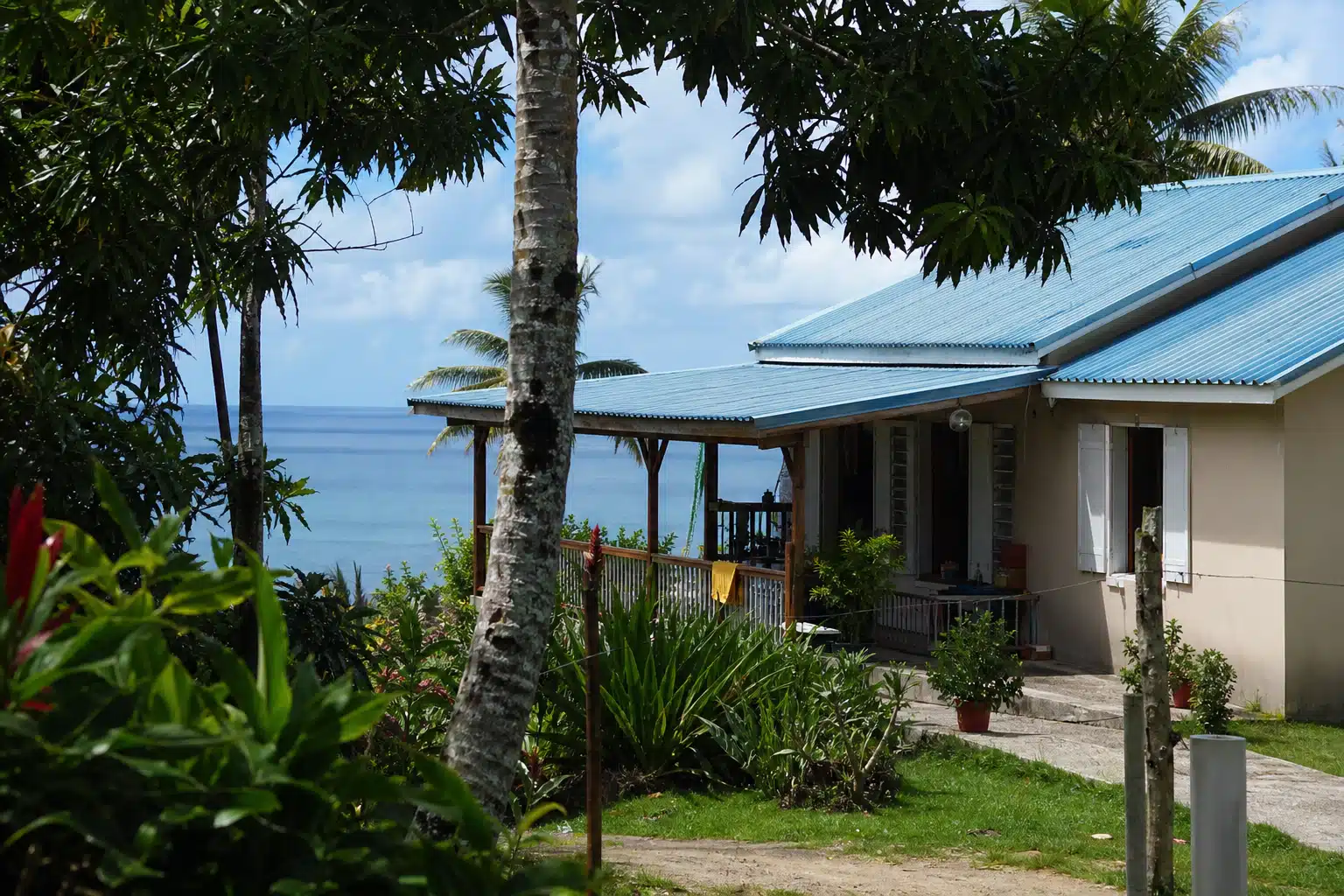 Bungalow côtier avec palmiers et vue sur l'océan.